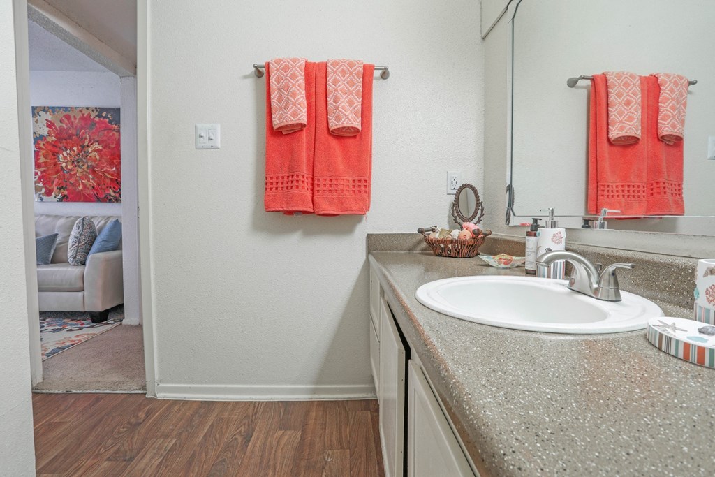 A bathroom with a spacious vanity with a white sink and orange towels at Laurel Parc apartments in Shreveport, LA.
