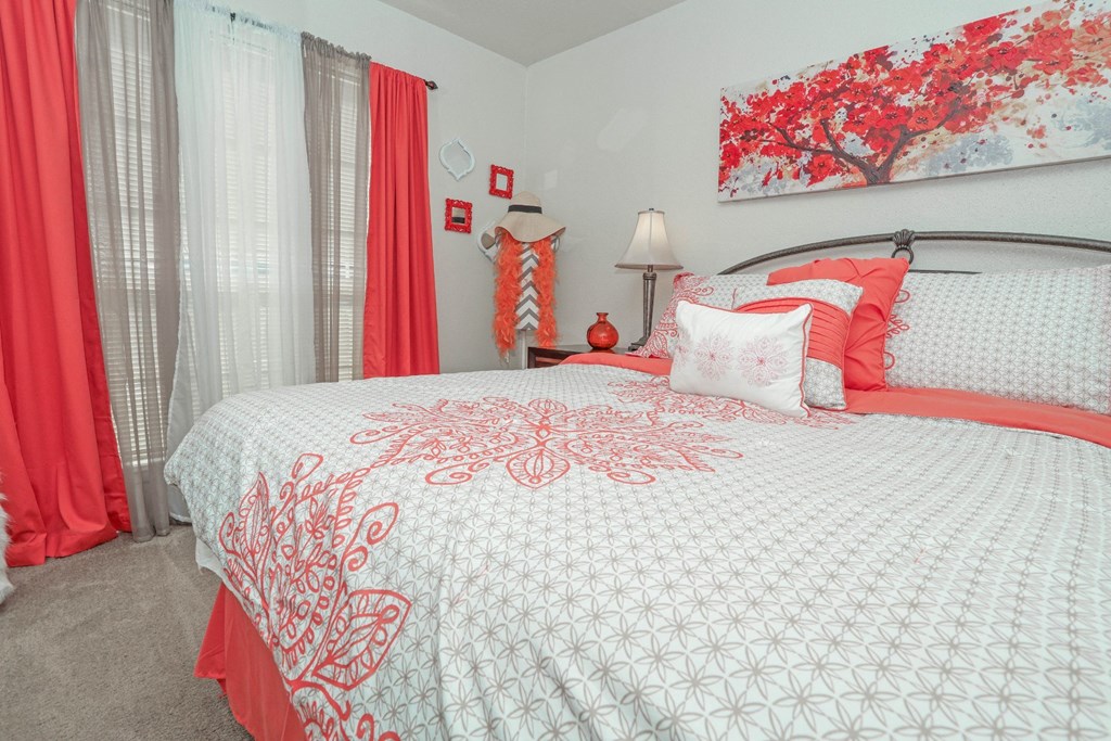 A bed with a white comforter and red pillows in our model apartment at Laurel Parc apartments in Shreveport, LA.
