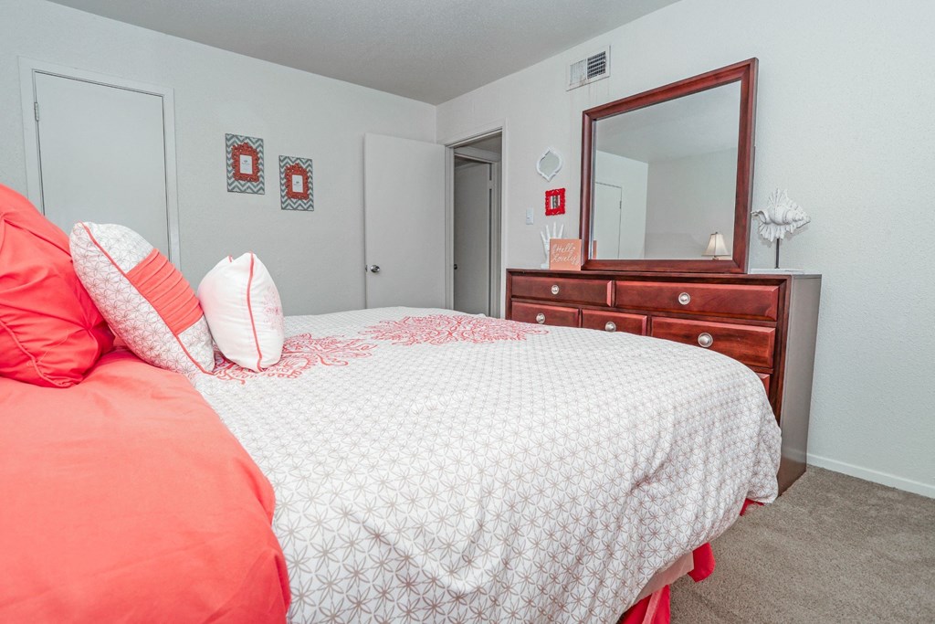 Model apartment bedroom with a bed, dresser, and mirror at Laurel Parc apartments in Shreveport, LA.
