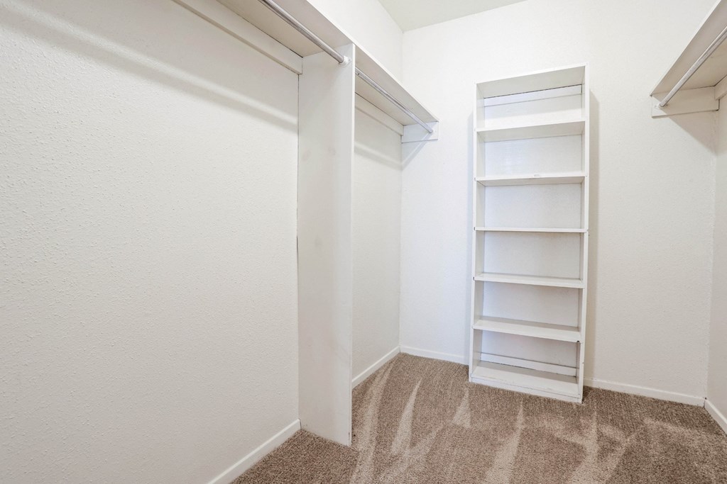 Spacious walk-in closet with built-in shelving and a carpeted floor at Laurel Parc apartments in Shreveport, LA.