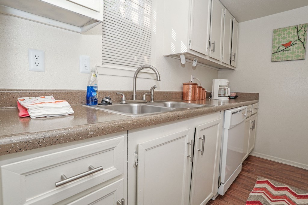 A kitchen with white cabinets and a double basin sink at Laurel Parc apartments in Shreveport, LA.