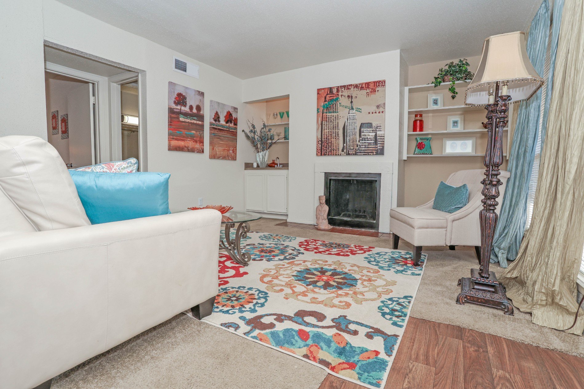 A living room with a white couch and a colorful rug.