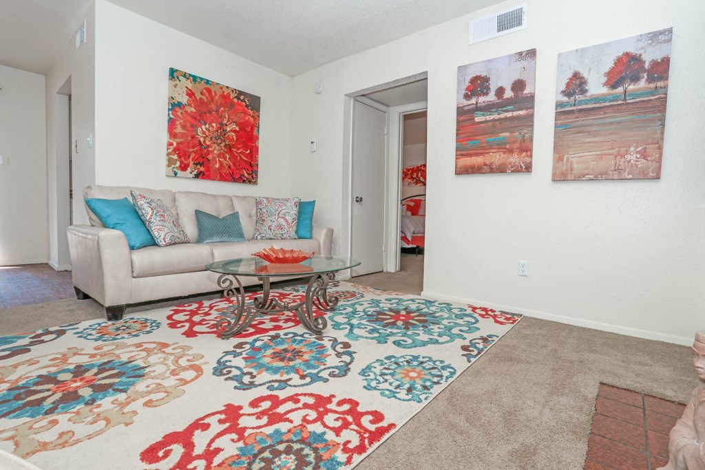 Model living room with a couch, rug and two paintings on the wall at Laurel Parc apartments in Shreveport, LA.