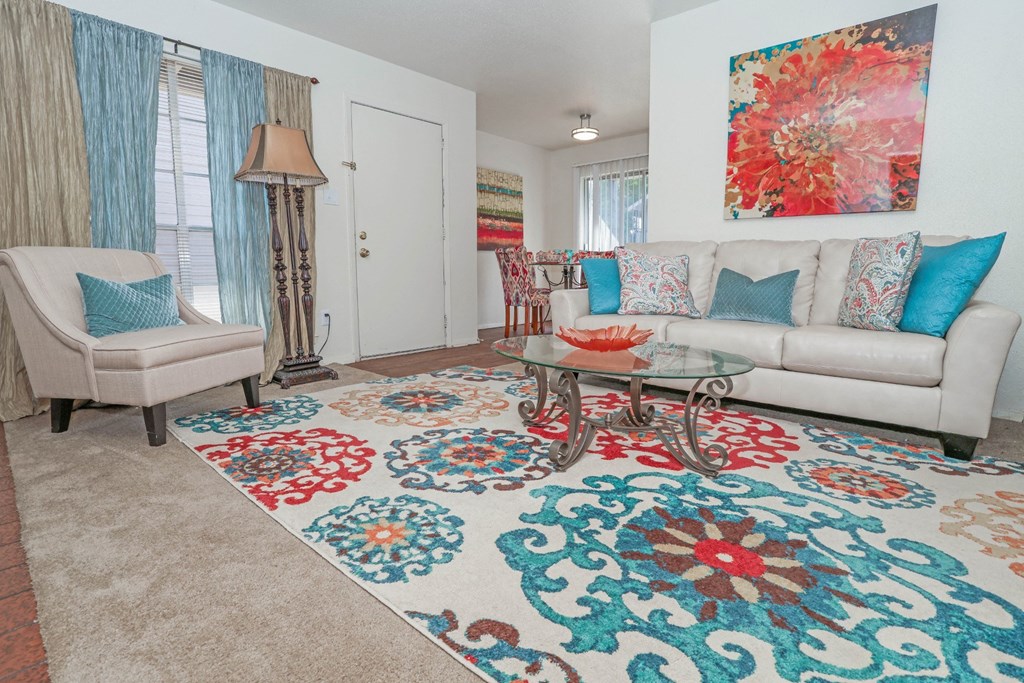 Large model living room with a white couch and a large floral rug at Laurel Parc apartments in Shreveport, LA.
