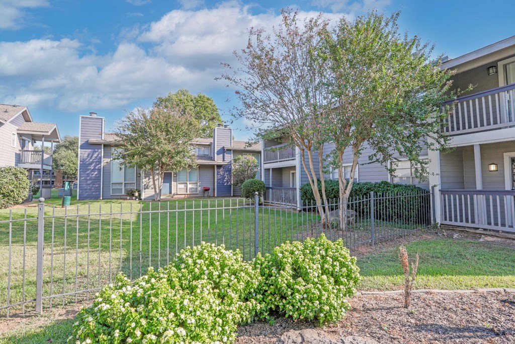Lush landscaping with apartment buildings in the background at Laurel Parc apartments in Shreveport, LA.