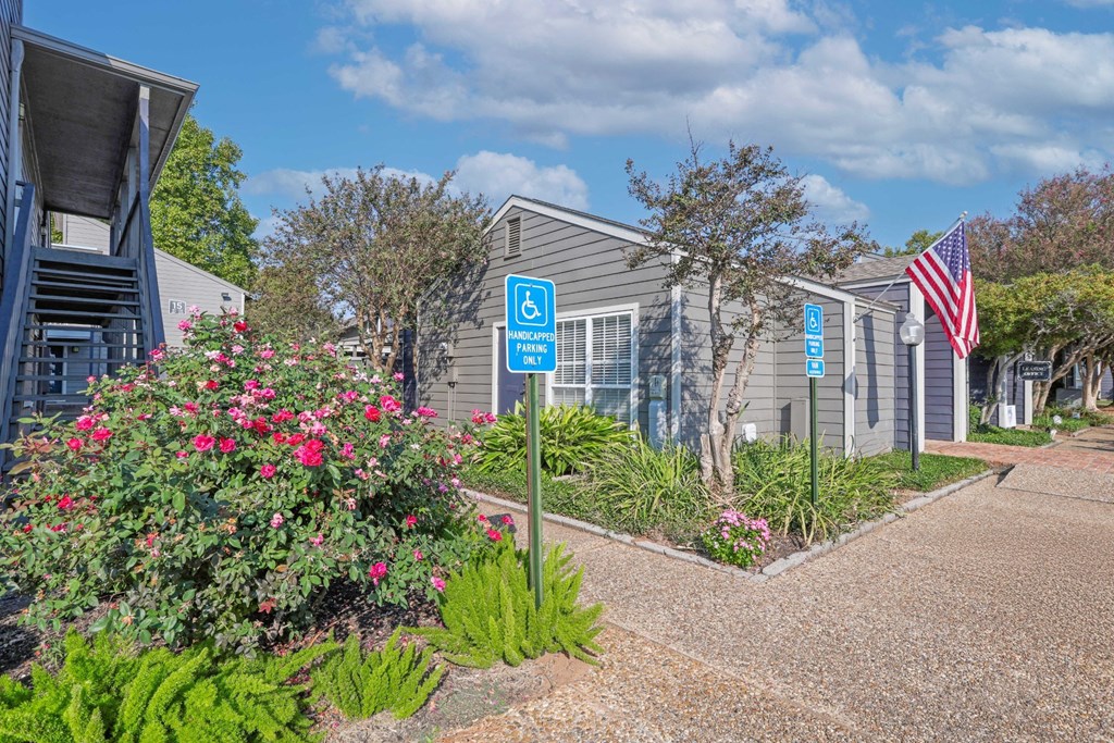 Beautiful landscaping next to the leasing office and signs for handicap parking at Laurel Parc apartments in Shreveport, LA.
