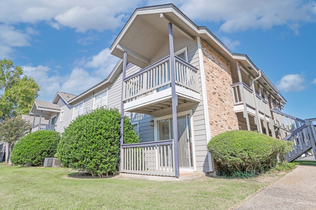 A two-story apartment building with a view of a balcony and patio for each unit at Laurel Parc apartments in Shreveport, LA.