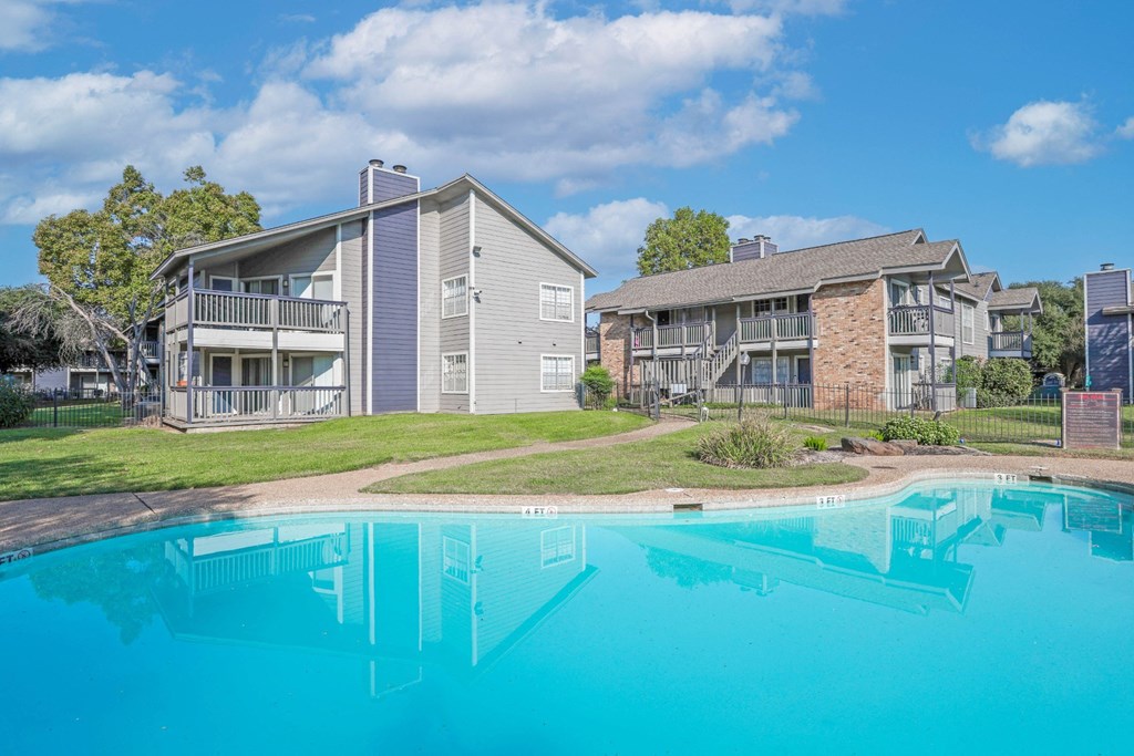 A swimming pool in front of apartment buildings at Laurel Parc apartments in Shreveport, LA.