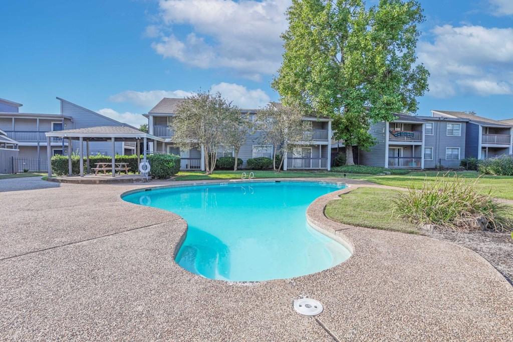 Our sparkling swimming pool with apartment buildings in the background at Laurel Parc apartments in Shreveport, LA.