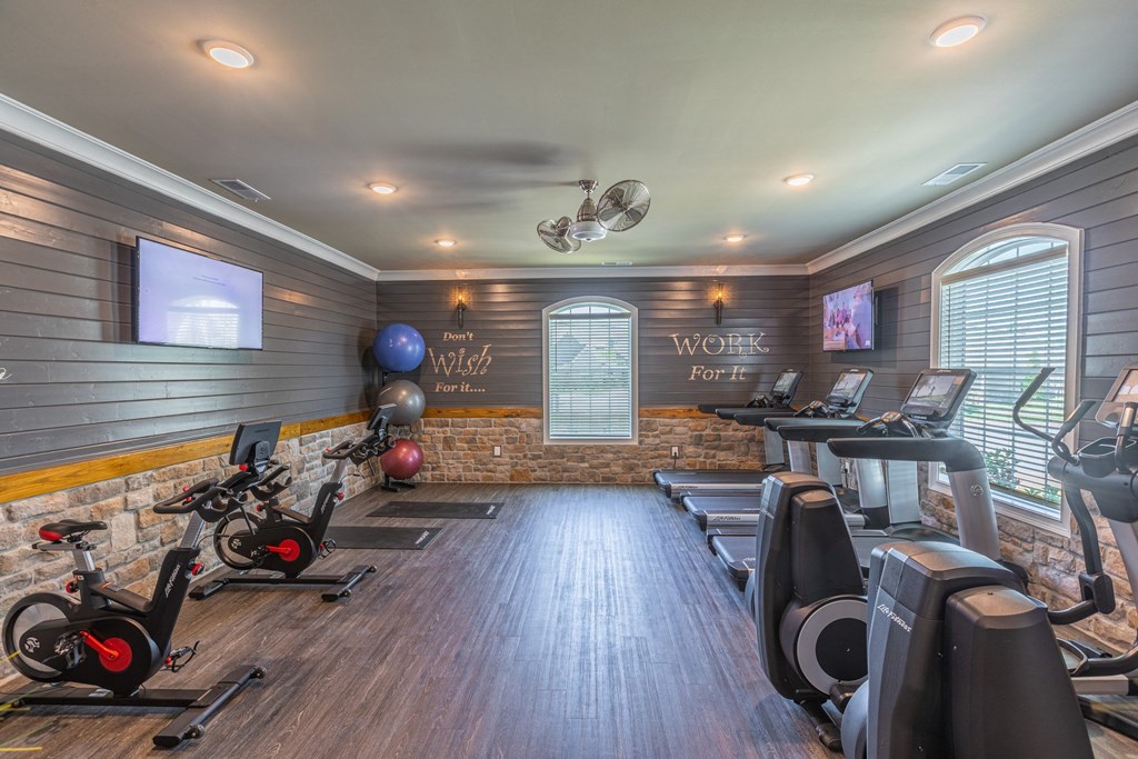 a gym with treadmills and other workout equipment and a tv on the wall
