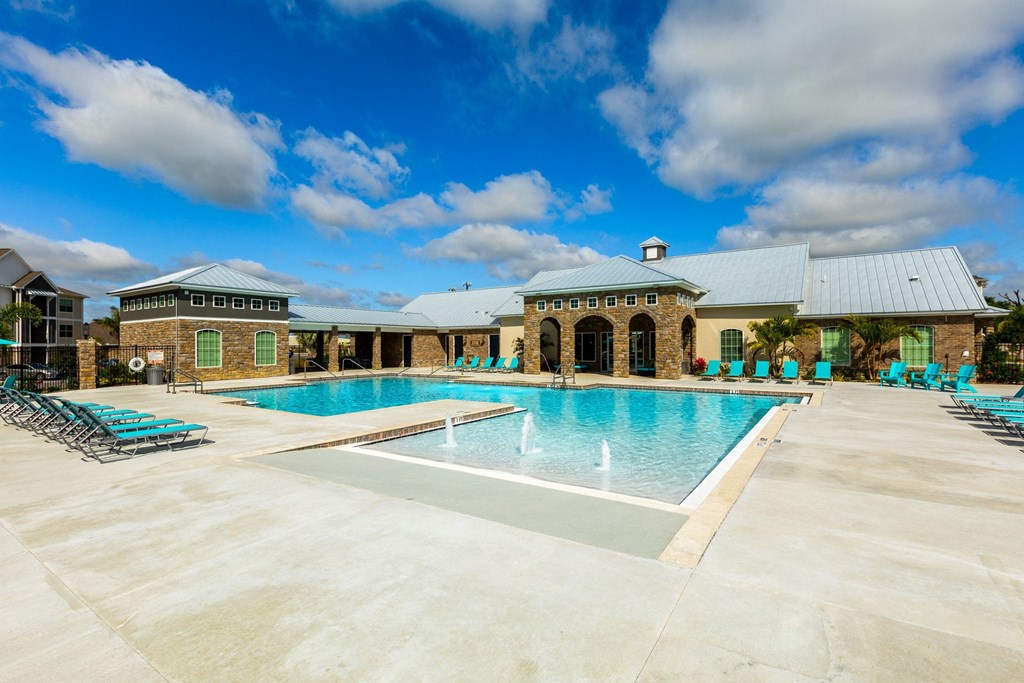 a swimming pool with chairs around it in front of a building