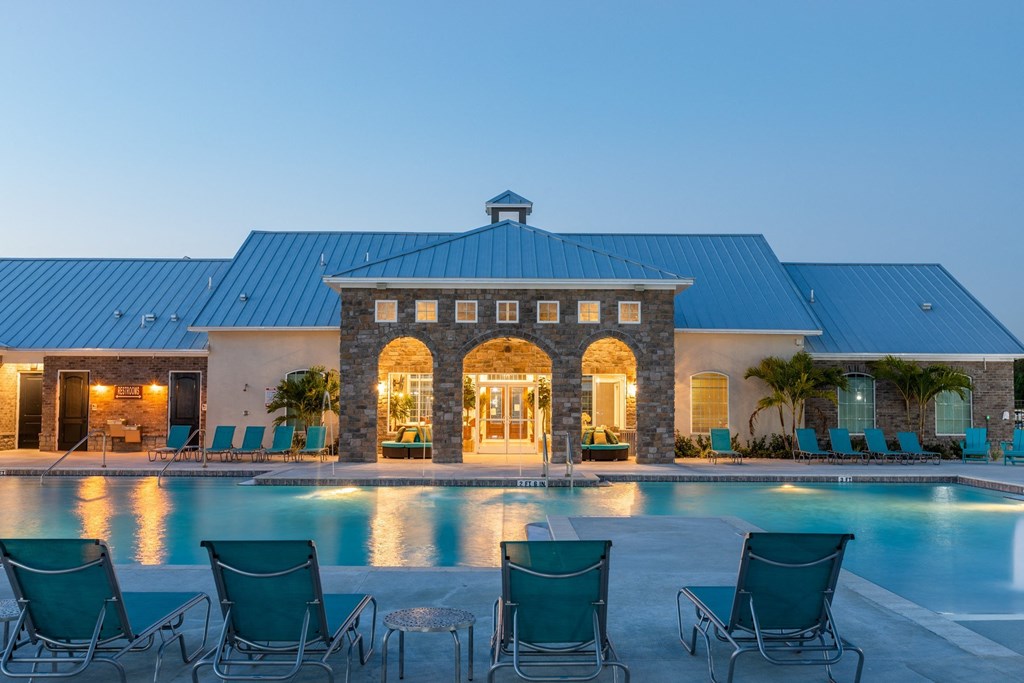 a swimming pool with chairs around it in front of a building