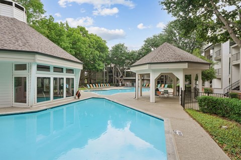 A swimming pool with a pavilion and a person walking.