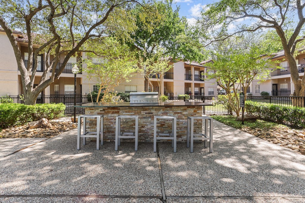 a patio with a table and chairs and trees in the background