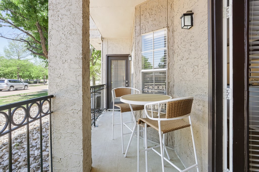 a balcony with a table and chairs and a tree in the background