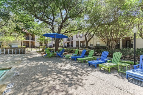 a group of lawn chairs and umbrellas in front of an apartment building