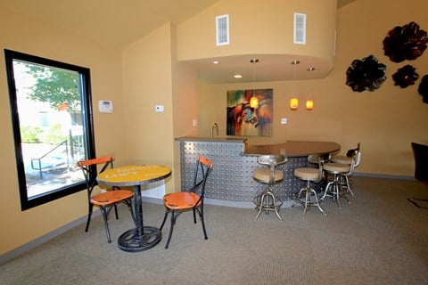 a dining area with tables and chairs and a bar with a large window