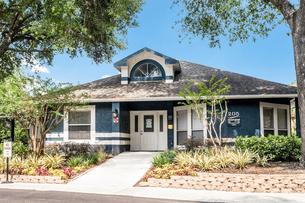 Leasing office exterior with lush landscaping at Reflections Apartments in Gainesville, FL