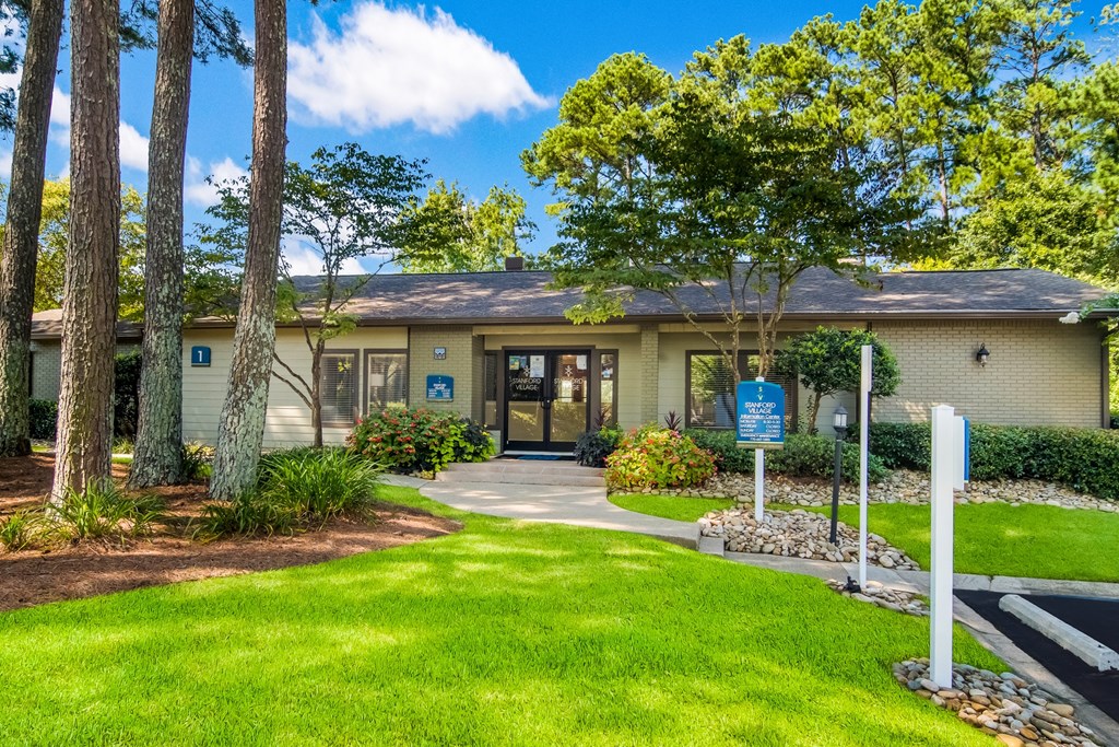 the front of a house with a green lawn and trees