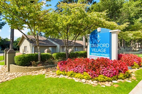 a sign that says stanford village with a house in the background