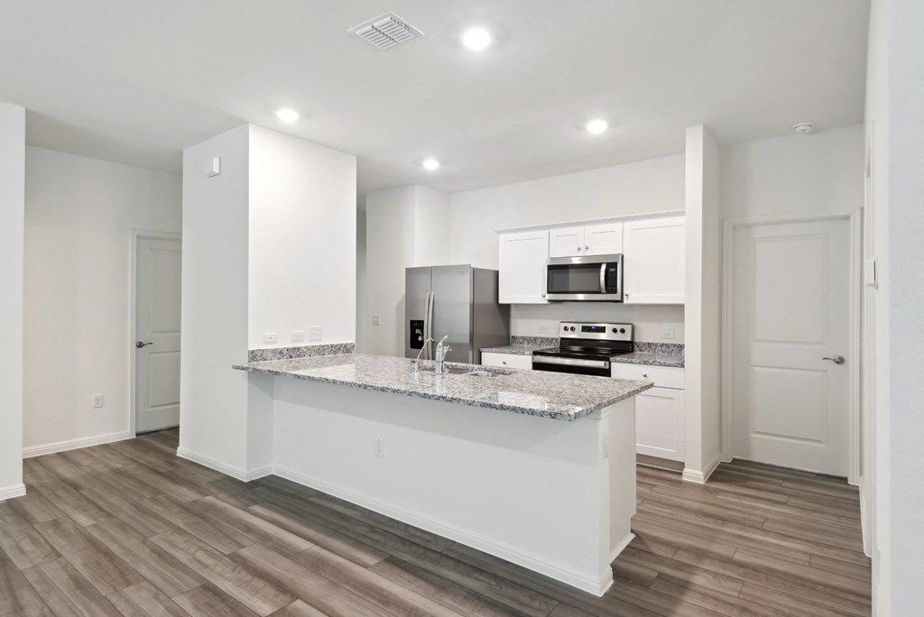 the kitchen with granite countertop and white cabinets