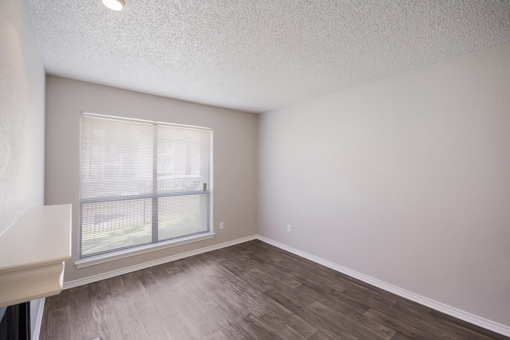 an empty living room with a large window and wood flooring
