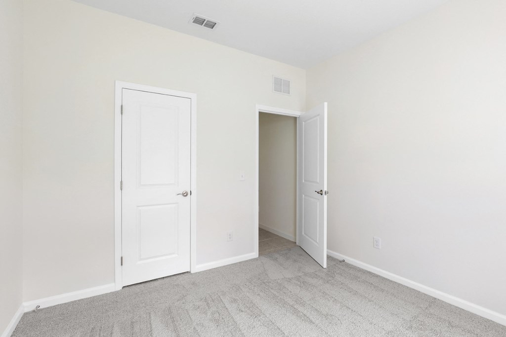 a bedroom with two doors and a carpeted floor