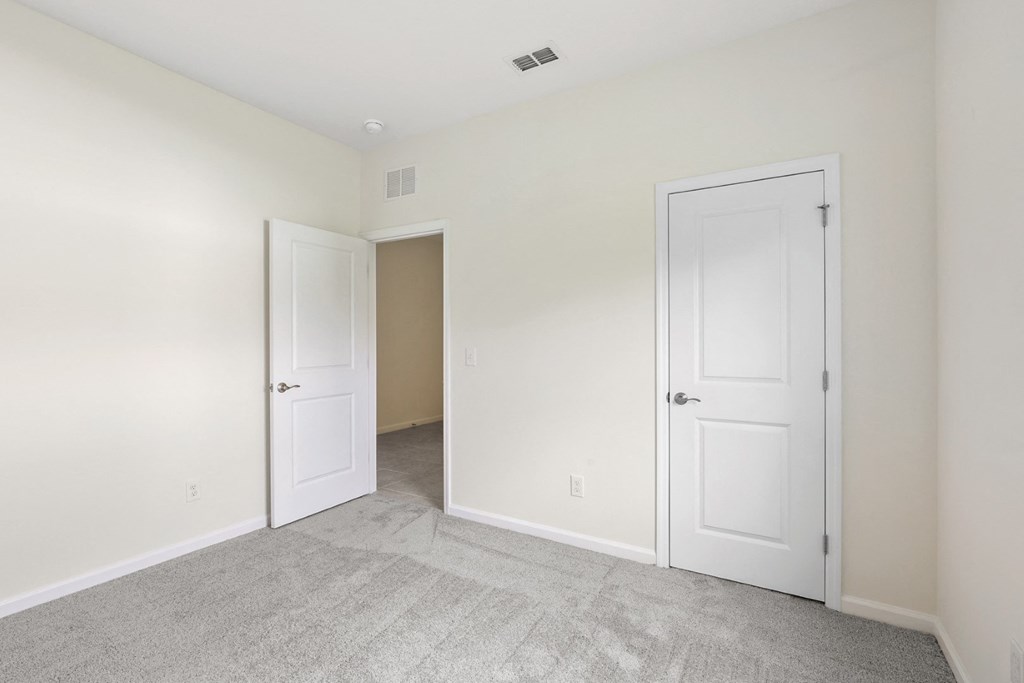 a bedroom with two doors and a carpeted floor