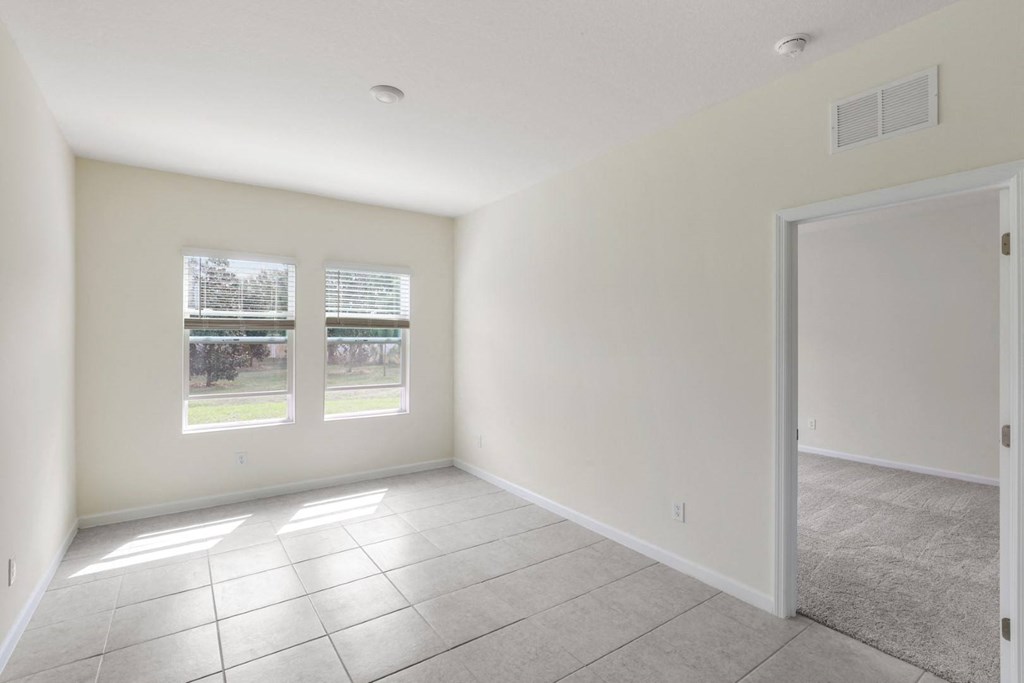 a bedroom with white walls and a tiled floor