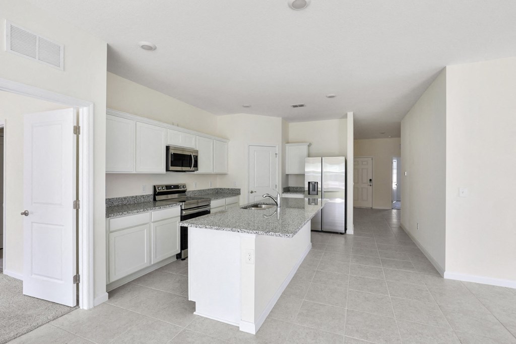 a large kitchen with white cabinets and granite countertops