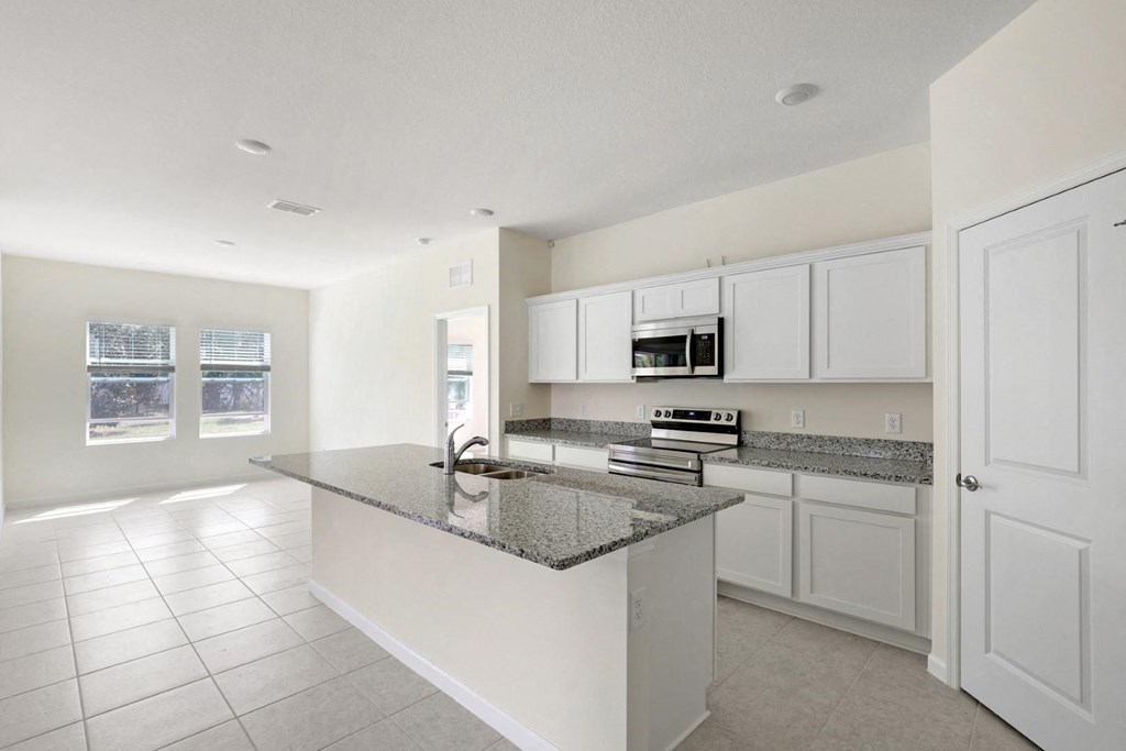 a kitchen with white cabinets and a granite counter top