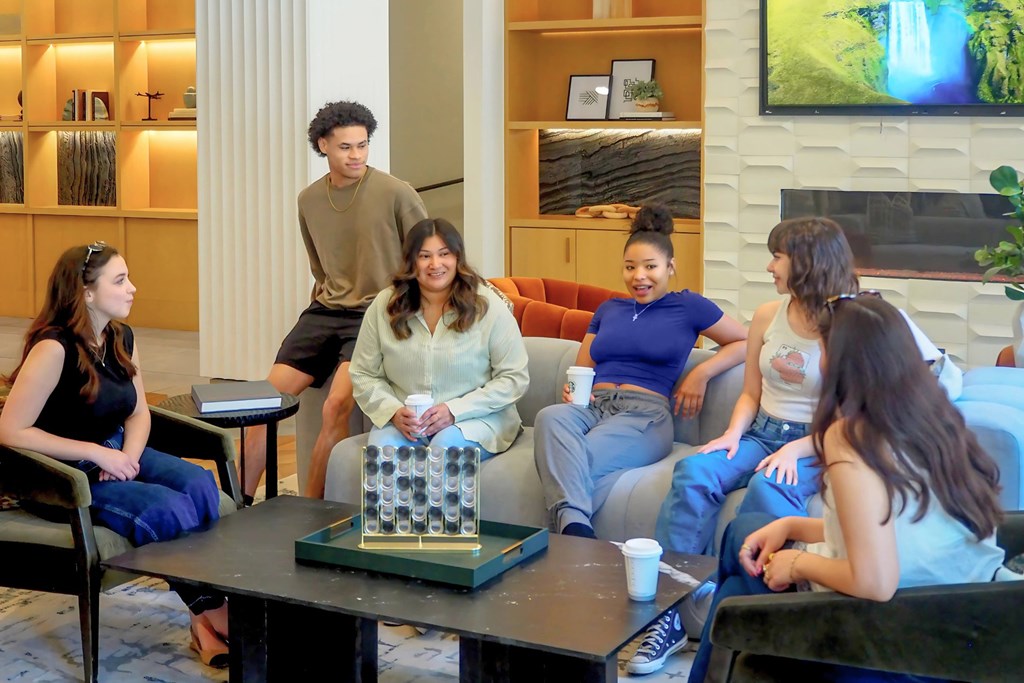 A group of people are sitting around a table in the amenities center at Era in Denton, TX