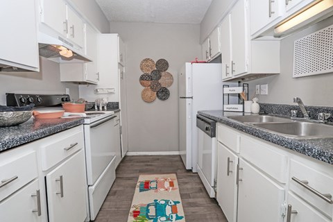 A kitchen with white cabinets and a grey counter top at Maplewood apartments in Shreveport, LA..