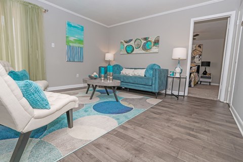 A cypress living room with a white chair and a blue couch at The Marq in Shreveport, LA