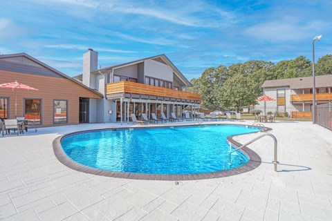 A large outdoor swimming pool surrounded by a patio area with lounge chairs and umbrellas at The Marq apartments in Shreveport, LA