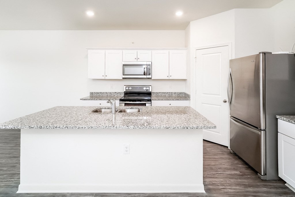 a kitchen with white cabinets, granite countertops and stainless steel appliances