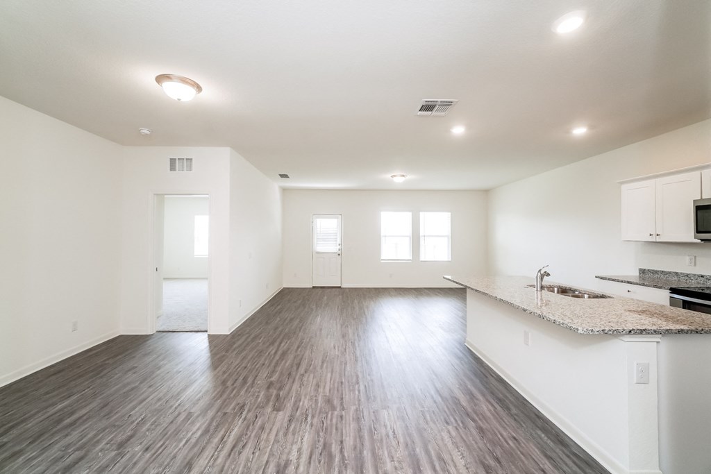 the modern living room and kitchen with white walls, windows a granite countertop