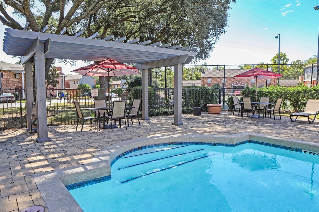 a swimming pool with patio furniture and umbrellas