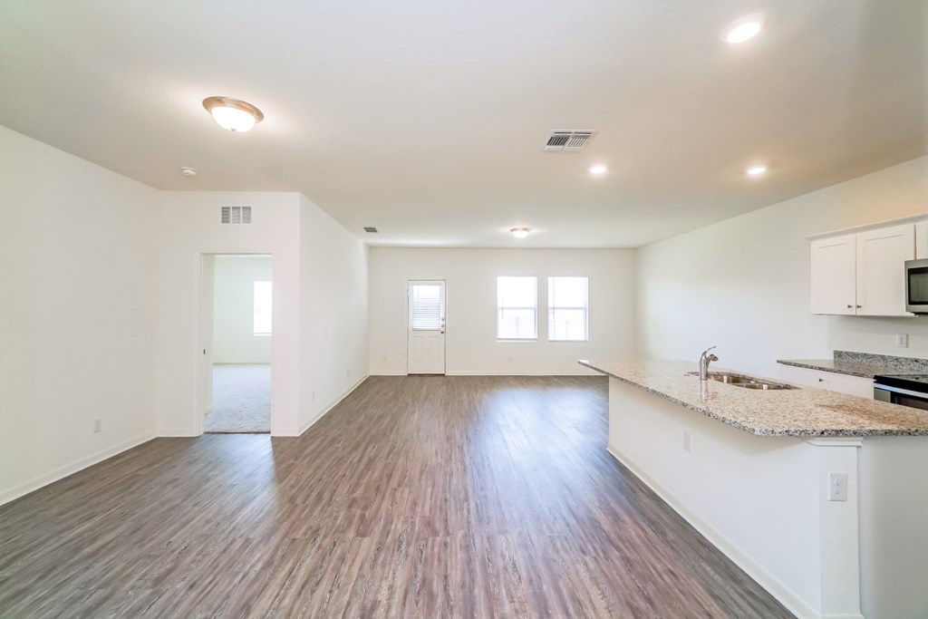an empty living room and kitchen area with a granite countertop at Beacon at Meridian, Texas
