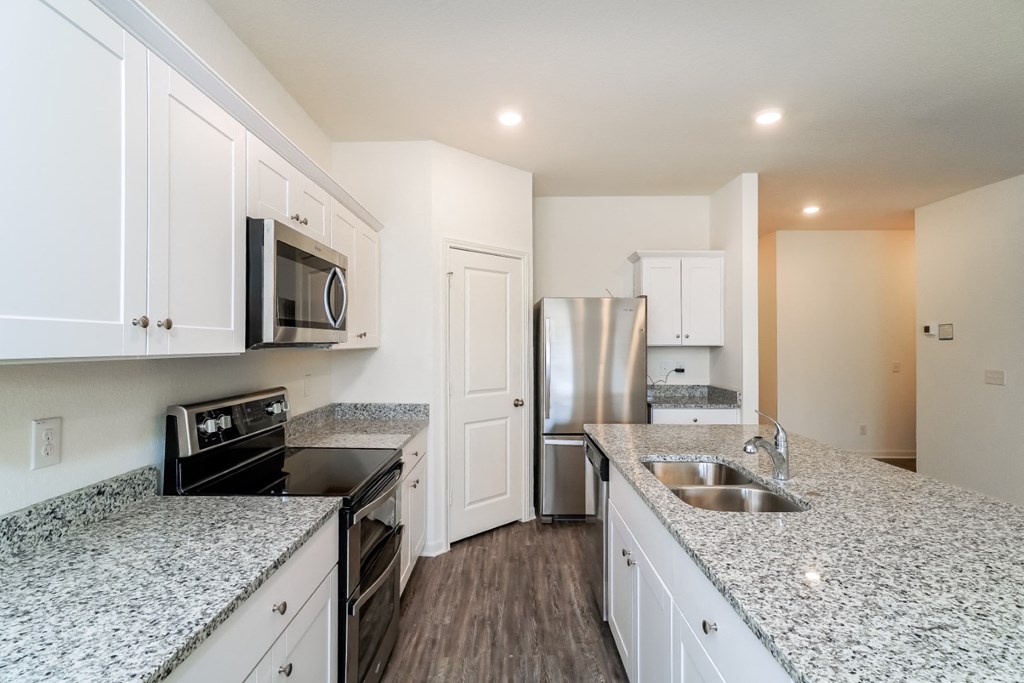 a kitchen with granite countertops and white cabinets at Beacon at Meridian, San Antonio, TX