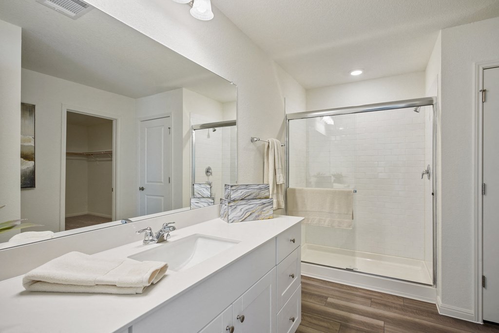 a white bathroom with a large mirror and a shower