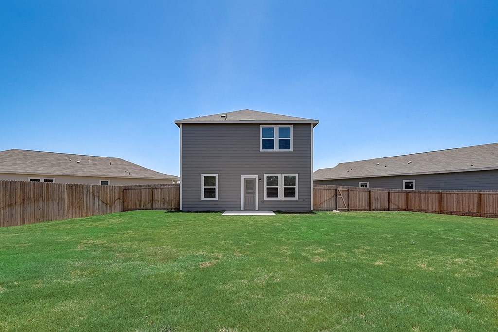 a backyard with a gray house and a wooden fence at Beacon at Meridian, San Antonio Texas