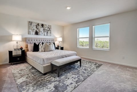 a bedroom with a large bed and two windows at Beacon at Meridian, San Antonio, 78245