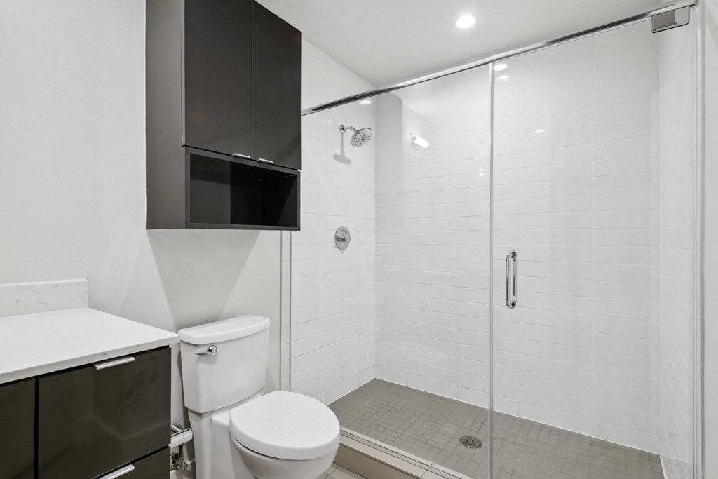 Bathroom with towel cabinet over toilet and a large walk-in shower at Mid Elm Lofts in Dallas, TX