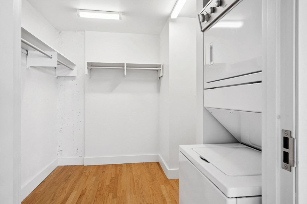 Spacious walk-in closet with a stacked washer and dryer and polished wood floors at Mid Elm Lofts in Dallas, TX
