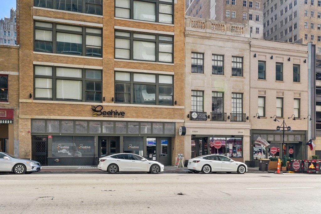 View from across the street of the Mid Elm Lofts Building with retail spots around at Mid Elm Lofts in Dallas, TX