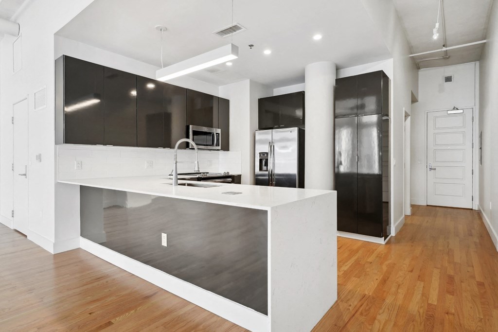 Large kitchen with ample counterspace, modern and sleek black cabinets, and stainless steel appliances at Mid Elm Lofts in Dallas, TX