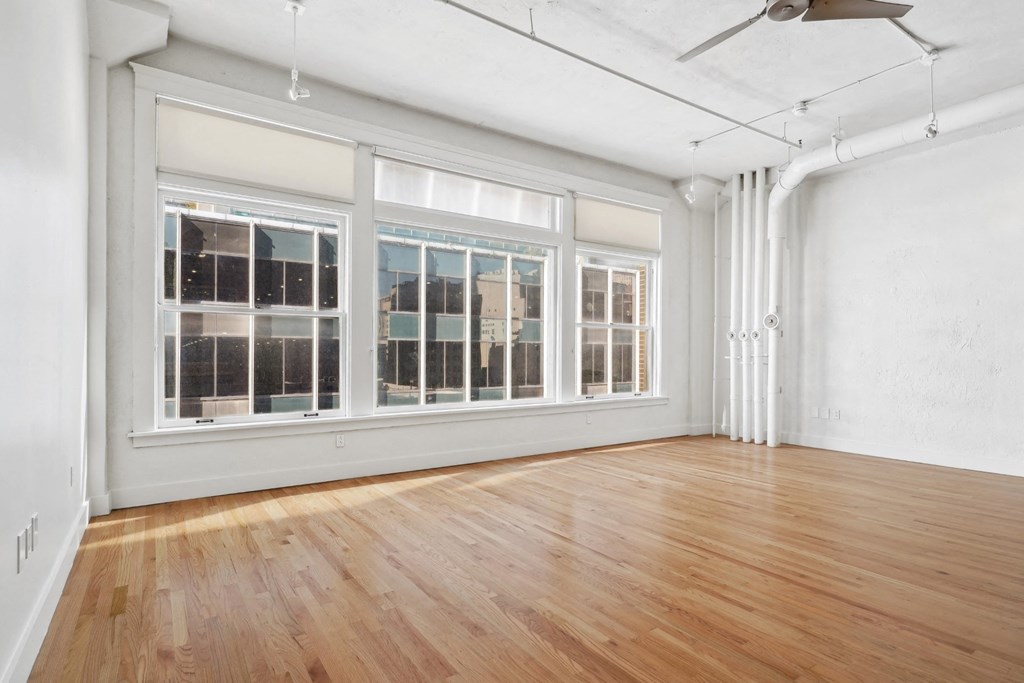 View of large living room with urban accents, polished wood floors and large windows at Mid Elm Lofts in Dallas, TX