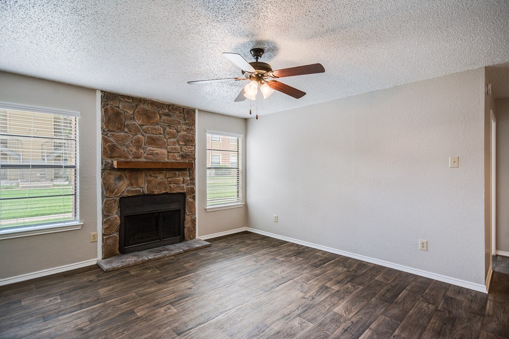 Living Room with Fireplace and Ceiling Fan at Bookstone and Terrace Apartments in Irving, Texas