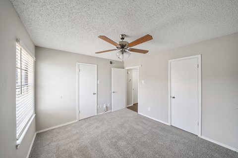 an empty bedroom with a ceiling fan